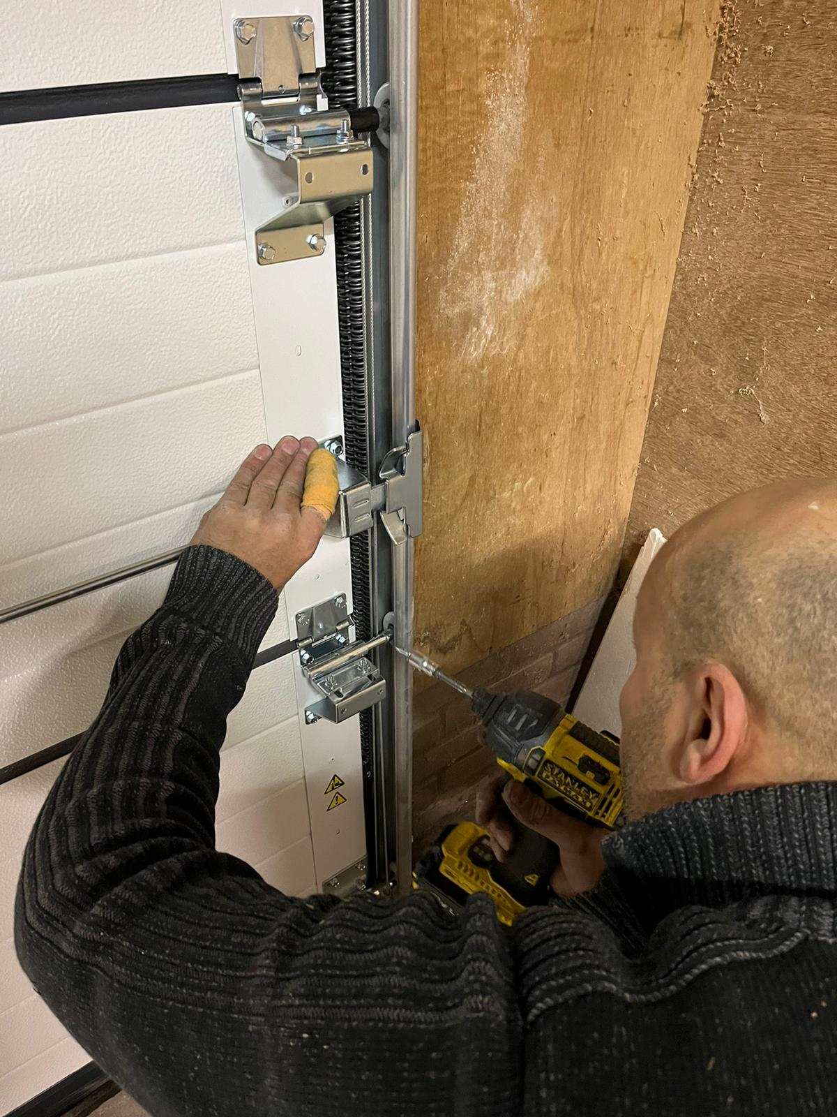 Monteur monteert sectionale garagedeur met elektrische aandrijving